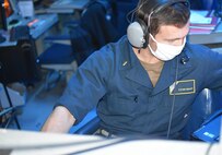210221-N-NO146-1001 GULF OF OMAN (Feb. 21, 2021) - Ensign Steven Midkiff monitors communications in the combat information center aboard guided-missile cruiser USS Port Royal (CG 73) during a joint air defense exercise in the Gulf of Oman, Feb. 21. Port Royal is deployed to the U.S. 5th Fleet area of operations in support of naval operations to ensure maritime stability and security in the Central Region, connecting the Mediterranean and Pacific through the western Indian Ocean and three critical chokepoints to the free flow of global commerce. (U.S. Navy courtesy photo)
