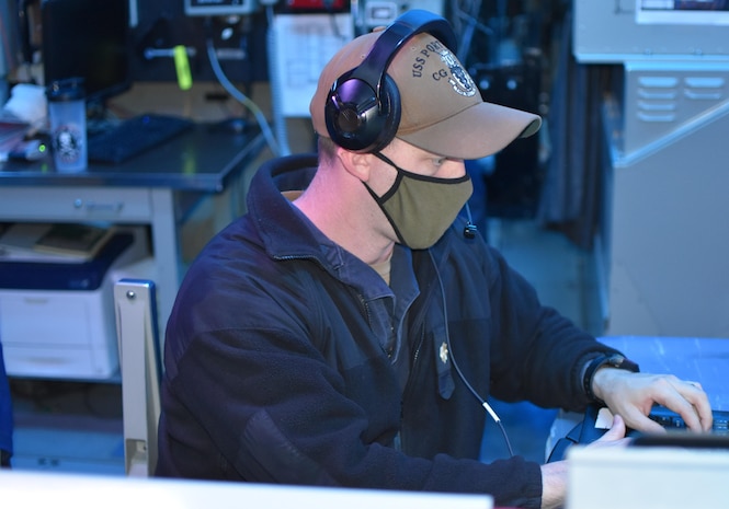 210221-N-NO146-1001 GULF OF OMAN (Feb. 21, 2021) - Lt. Cmdr. Chris Bradley stands watch as tactical action officer in the combat information center aboard guided-missile cruiser USS Port Royal (CG 73) during a joint air defense exercise in the Gulf of Oman, Feb. 21. Port Royal is deployed to the U.S. 5th Fleet area of operations in support of naval operations to ensure maritime stability and security in the Central Region, connecting the Mediterranean and Pacific through the western Indian Ocean and three critical chokepoints to the free flow of global commerce. (U.S. Navy courtesy photo)