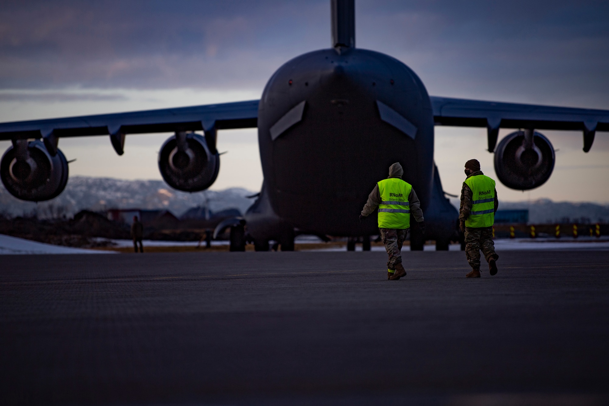 Airmen assigned to the 9th Expeditionary Bomb Squadron walk toward a C-17 Globemaster III, assigned to the 437th Airlift Wing, on the flightline at Ørland Air Force Station, Norway, Feb. 23, 2021. The C-17 provided logistic support for cargo needed to perform Bomber Task Force missions throughout the European theater. (U.S. Air Force photo by Airman First Class Colin Hollowell)