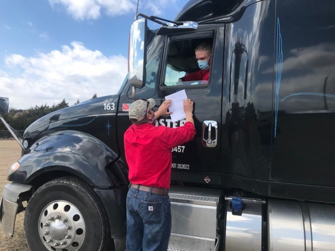 a man talks to another man in a big truck