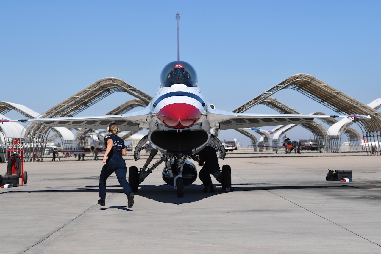 An airman runs toward the side of an aircraft.