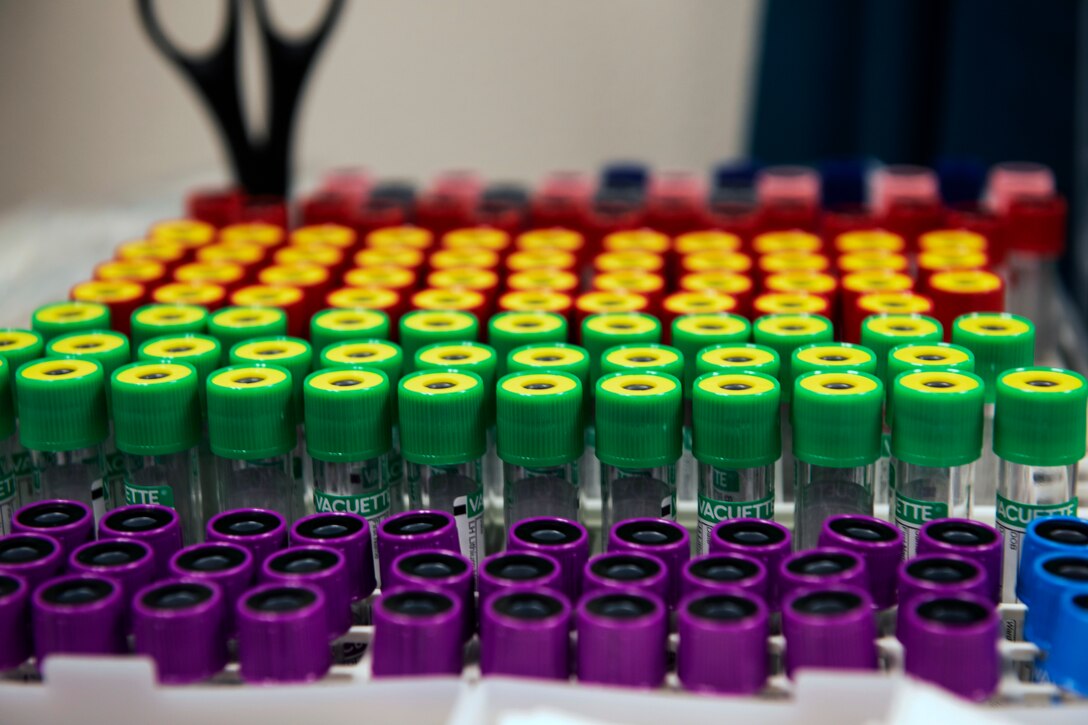 Boxes of different colored empty vials sit on a table.