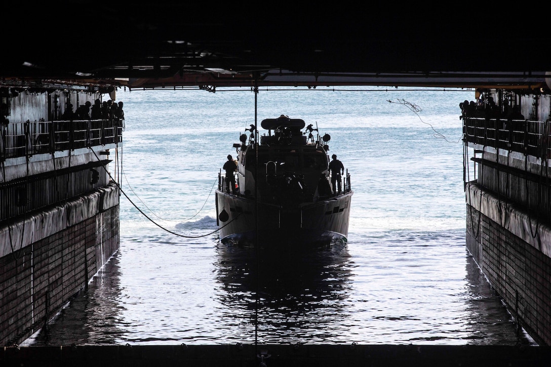 A boat enters the well deck of a ship.