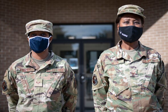 Two Airmen stand next to each other.