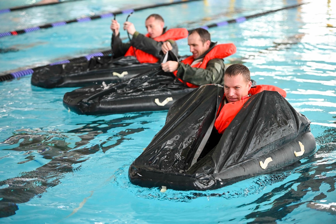 Three airmen float on small rafts in a pool.