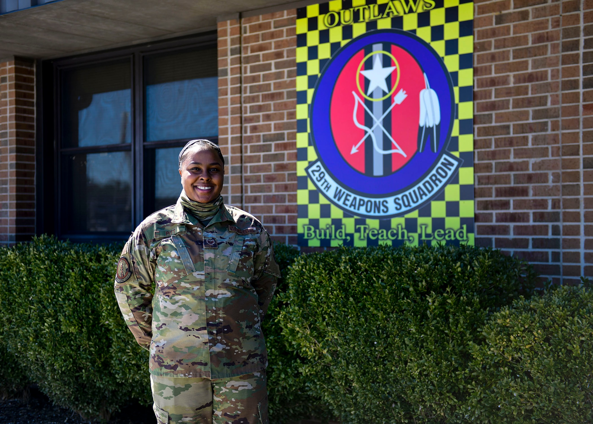 A woman poses for a photo in front of a squadron sign.