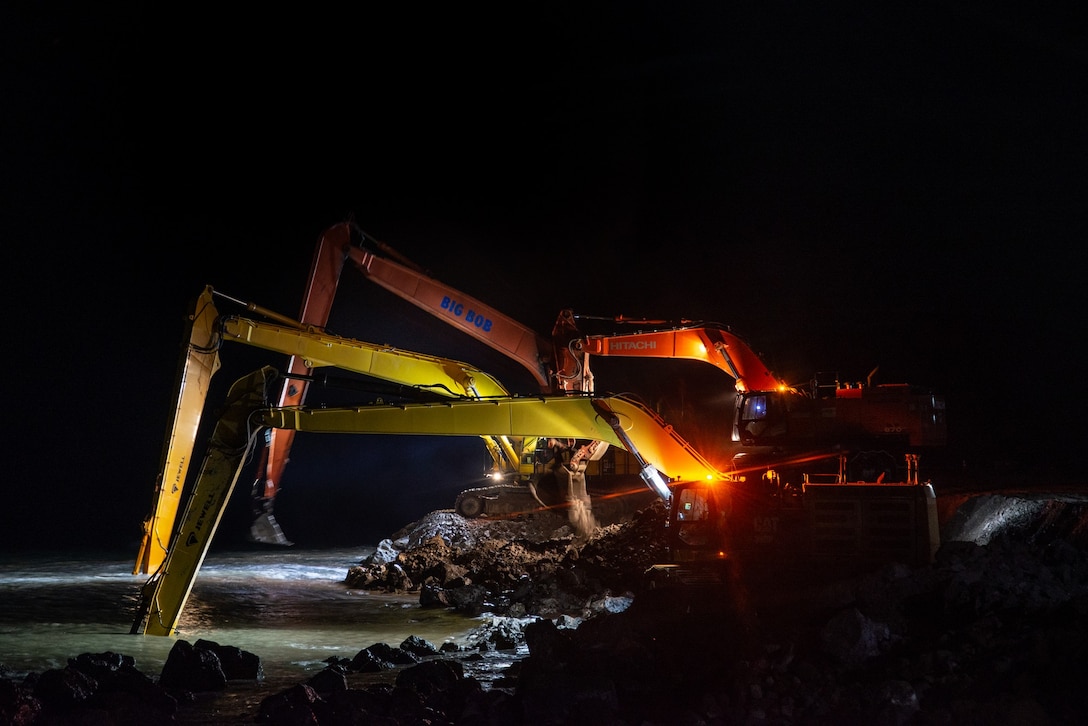 Long stick hydraulic excavators lay rocks in the late hours for the seawall repair at Cape Lisburne on Oct. 10, 2019.