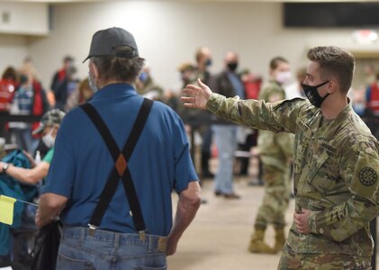 A Michigan Army National Guard Soldier serving with COVID-19 Vaccination Testing Team Task Force North directs a resident during a mass immunization clinic in Cheboygan, Michigan, Feb. 24, 2021.