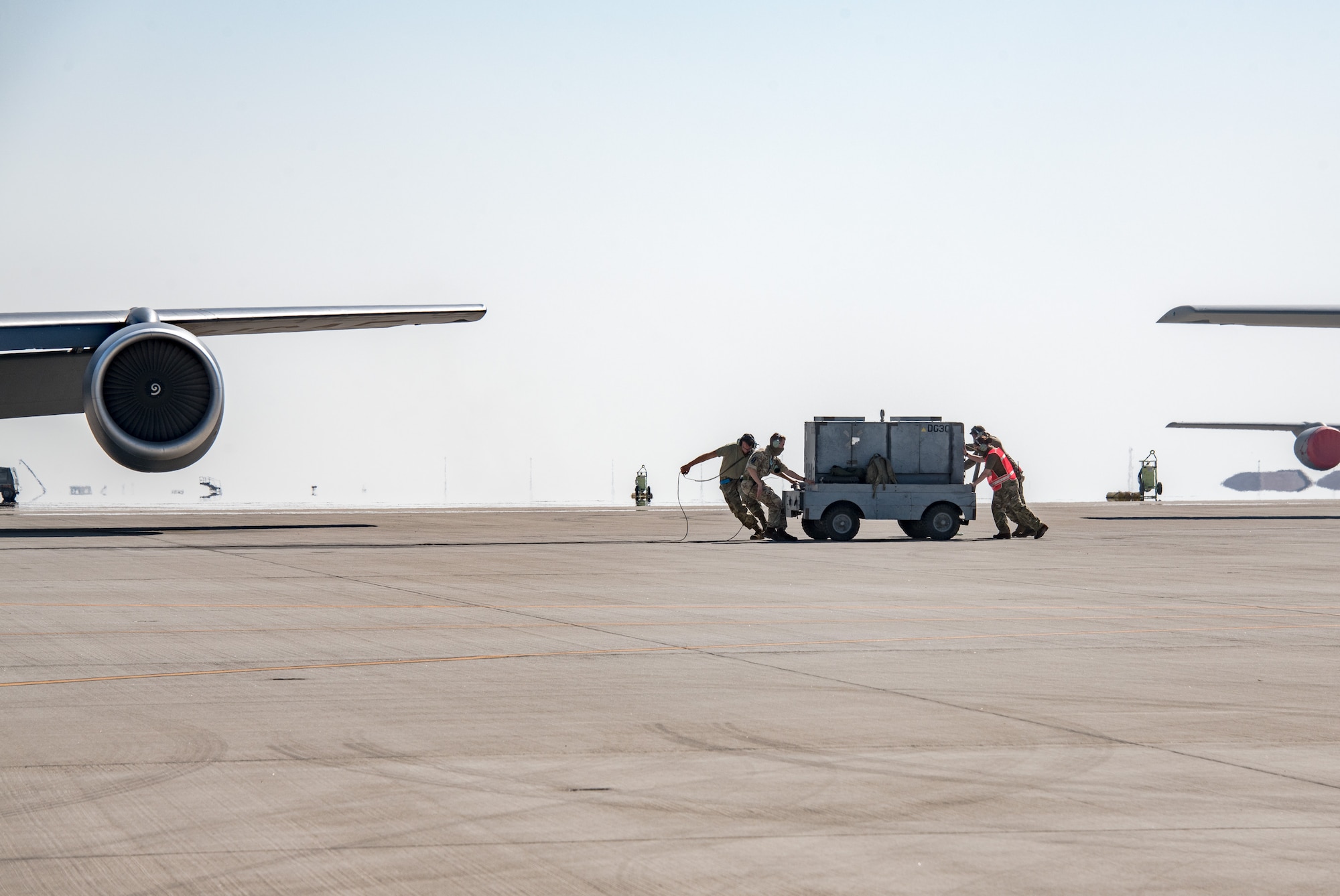 Airmen push a cart on a flightline