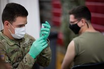U.S. Army Pfc. Tanner Tate, assigned to the 627th Hospital Center out of Fort Carson, Colo., prepares to administer a COVID vaccine to a fellow Soldier at a state-run, federally-supported Community Vaccination Center in Elizabeth, N.J..