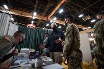Ernesto Hernandez, a lead clinician with the New Jersey State Department of Health, speaks with U.S. Army Pfc. Tazmin Salas at a state-run, federally-supported Community Vaccination Center in Elizabeth, N.J..