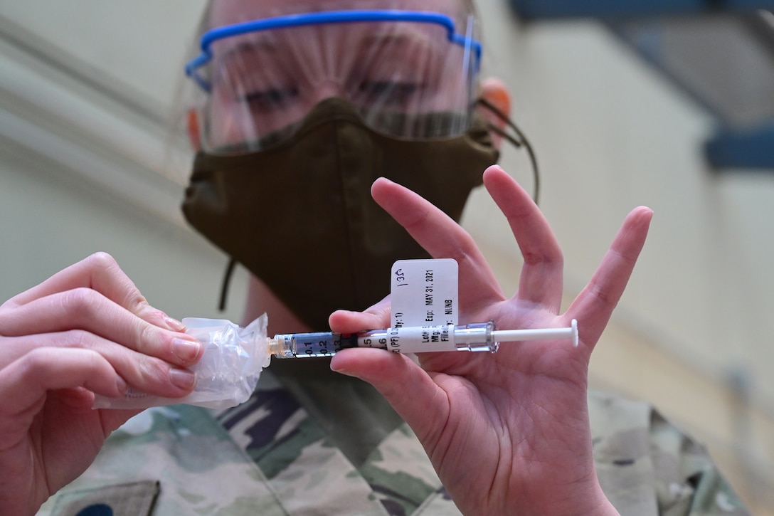 A soldier puts vaccine into a syringe.