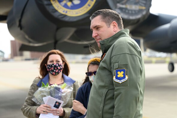 An Airman hugs his daughter as his wife looks on.