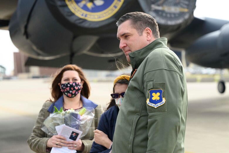 An Airman hugs his daughter as his wife looks on.