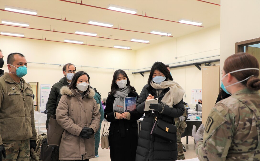 South Korean disease control workers listen to a U.S. soldier.