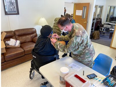 Staff Sgt. Herbert Lins, 3-238th Aviation (MEDEVAC) gives the COVID-19 vaccination to a patient at the CMC Retirement Village as part of the Targeted Vaccination Team in St. Louis, Mo. February 18, 2021