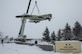 Members from the 3rd Maintenance Squadron assigned to the 3rd Wing, and Alaska Crane civilian contractors hoist the McDonnell F-4C Phantom II static display in front of the Government Hill Gate at Joint Base Elmendorf-Richardson, Alaska, Feb 18, 2021. This aircraft was accessioned by the National Museum of the United States Air Force in 1987 and was a former Hawaii Air National Guard fighter and is being moved temporarily for refurbishment. (U.S. Air Force photo by Senior Airman Adriana Barrientos)
