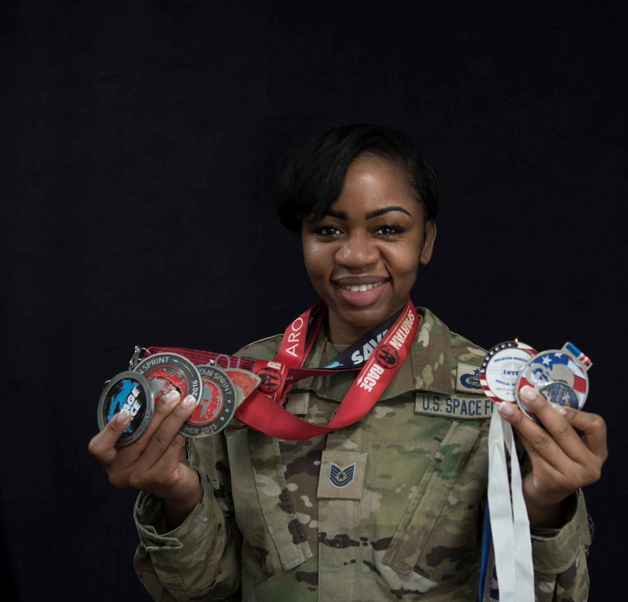 Tsgt. Shaneka hunter poses with her medals from various obstacle course races