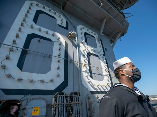 A Sailor mans the rails on the flight deck of the aircraft carrier USS Nimitz (CVN 68).