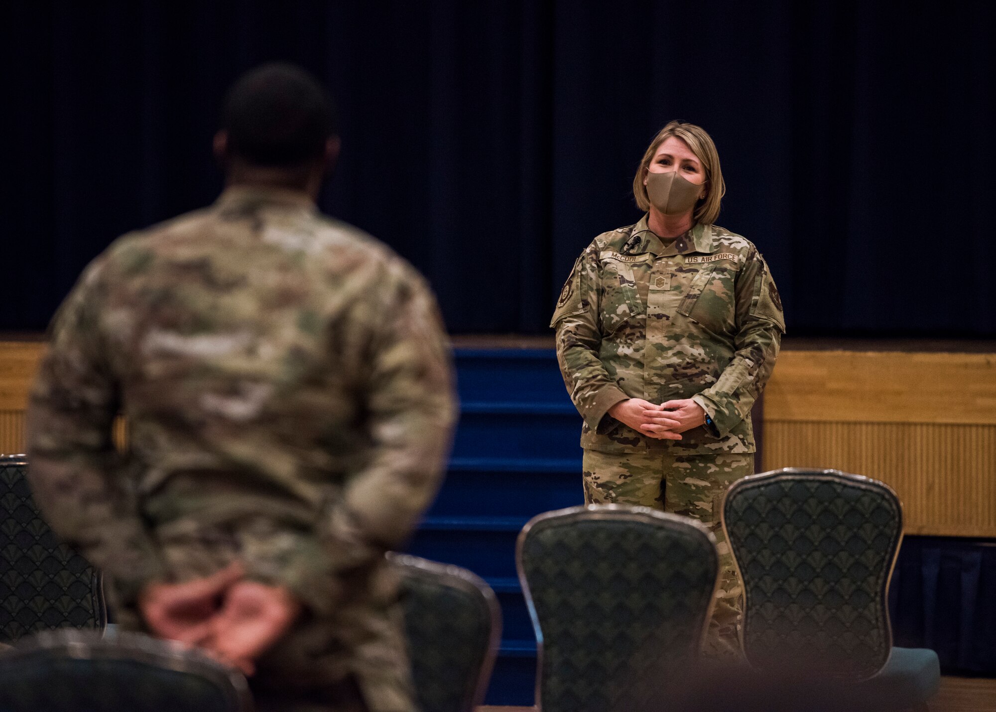 Man in uniform stands up to ask a question to woman in uniform.