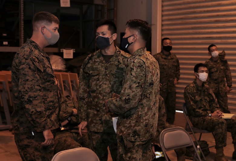 A U.S. Marine with 3rd Marine Expeditionary Brigade and members of the Amphibious Rapid Deployment Brigade of the Japan Ground Self-Defense Force talk before a rehearsal of concept drill for Exercise Yama Sakura 79 at Camp Courtney, Okinawa, Japan, Dec. 5, 2020.
