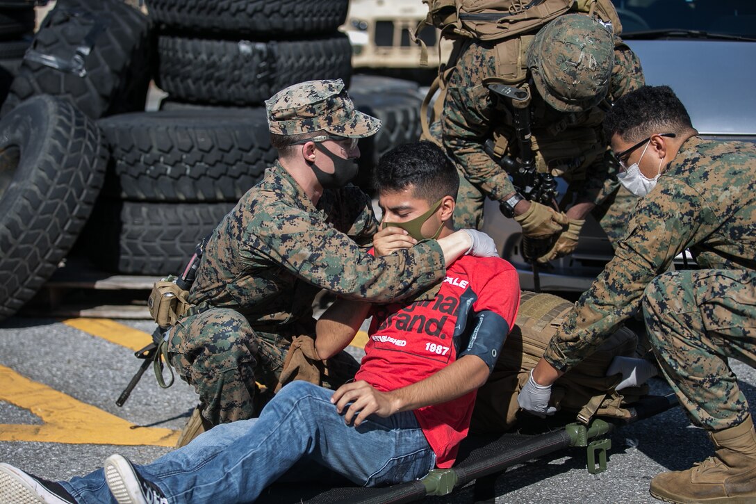 Marines with Combat Logistics Battalion (CLB) 31, 31st Marine Expeditionary Unit (MEU), move an evacuee role-player onto a stretcher during a noncombatant evacuation operation (NEO) rehearsal that took place after a simulated embassy reinforcement at Camp Hansen, Okinawa, Japan, Dec. 12, 2020. A NEO is the evacuation of civilians and nonessential military personnel from danger in an overseas country to a designated safe haven.