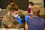 U.S. Army Spec. Kyle Hurley, a medic with the Michigan Army National Guard (MING), administers the COVID-19 vaccine to a health care worker at the Ascension Providence Hospital Southfield Campus in Southeast Michigan, Dec. 16, 2020.