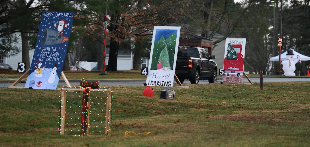 A truck passes by oversized greeting cards, Dec. 12, 2020, while attending the Children's Candy Cane Caravan at Arnold Air Force Base, Tenn. The greeting cards were made by Arnold Engineering Development Complex units. Attendees of the event voted for their favorite. (U.S. Air Force photo by Jill Pickett)