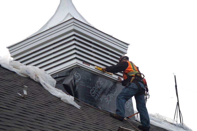 Workers inside and outside of the Auditorium building's new cupola guide it into place and ensure it is level.