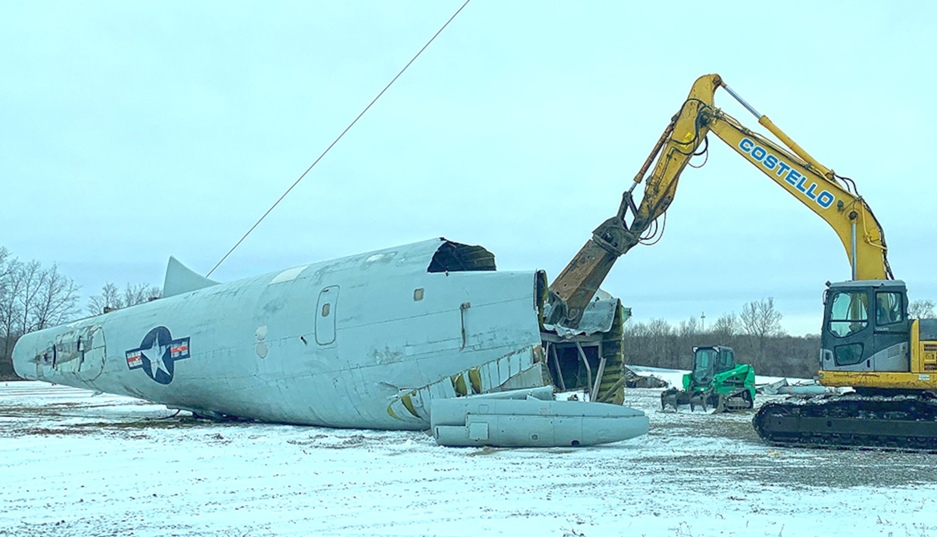 A large shearer tears apart a giant airframe in the snow.