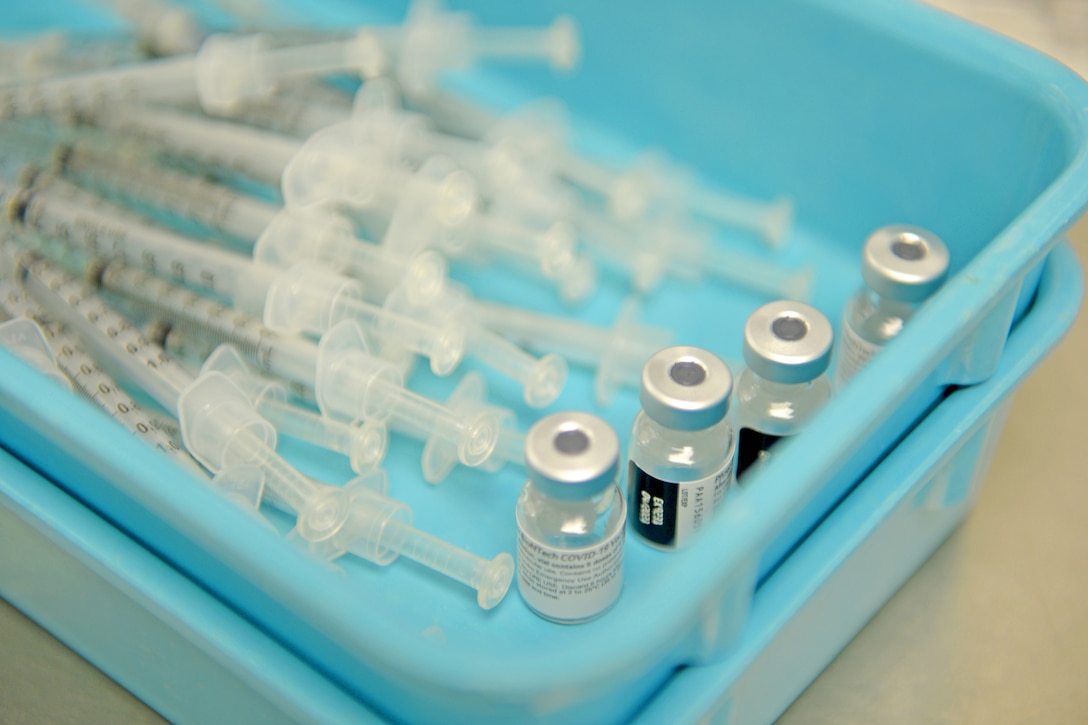 Syringes and small bottles of vaccine sit in a tray.