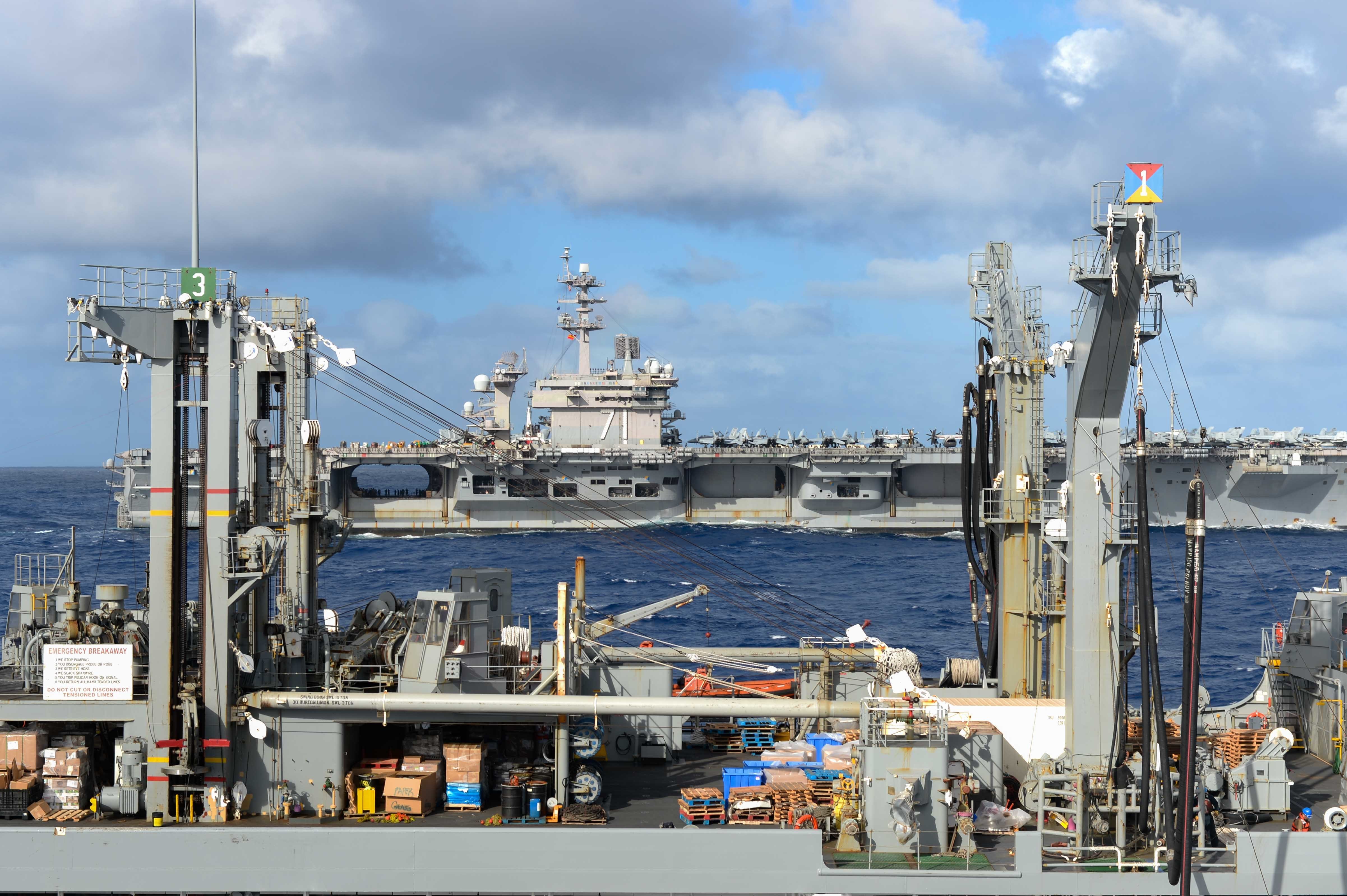 The aircraft carrier USS Theodore Roosevelt (CVN 71), back, transits alongside the Military Sealift Command fleet replenishment oiler USNS Guadalupe (T-AO 200).