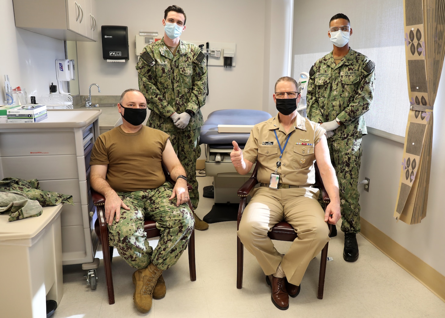 Rear Adm. Michael Wettlaufer, Commander, Military Sealift Command (right) and Command Master Chief Theron Fisher, Military Sealift Command's Command Master Chief (left), pose for a photograph  with U.S. Navy medical personnel after receiving their first dose of the COVID-19 vaccination at the Sewell's Point Branch Medical Clinic in Norfolk, Va., Jan. 4, 2021.