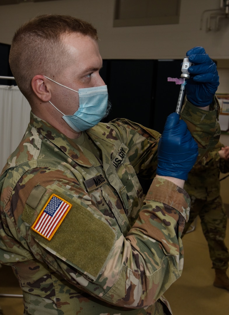 Sgt. Stephen Maynus prepares a dose of COVID-19 vaccine for delivery during a vaccine deployment at Camp Johnson, Vermont, Jan. 4, 2021. Thirty Soldiers and Airmen received vaccinations Jan. 4, with more shots scheduled for Jan. 6 and Jan. 8. Maynus is a health care clinic NCO with the Vermont Army National Guard Medical Detachment.