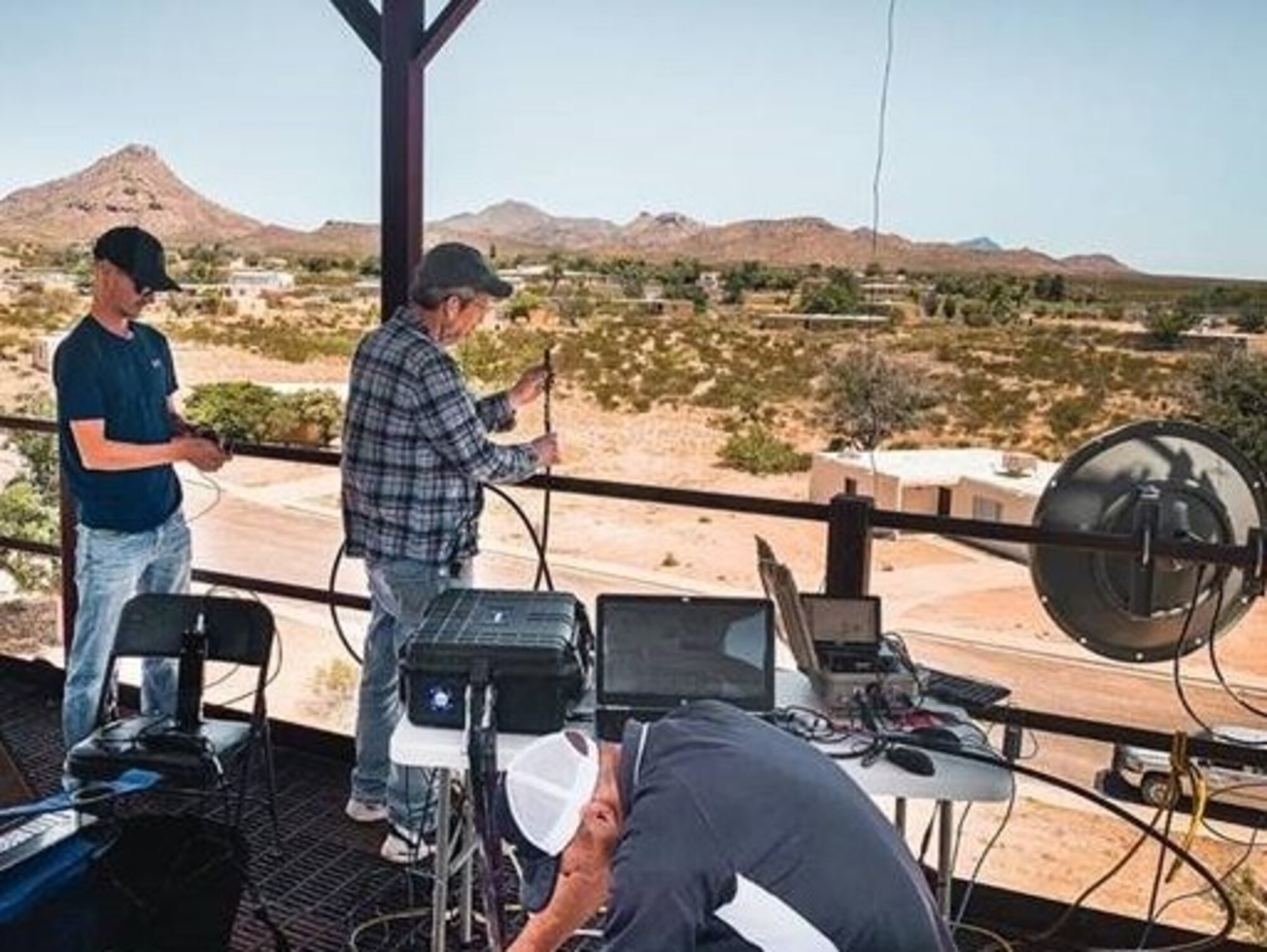 three men setting up equipment in the desert