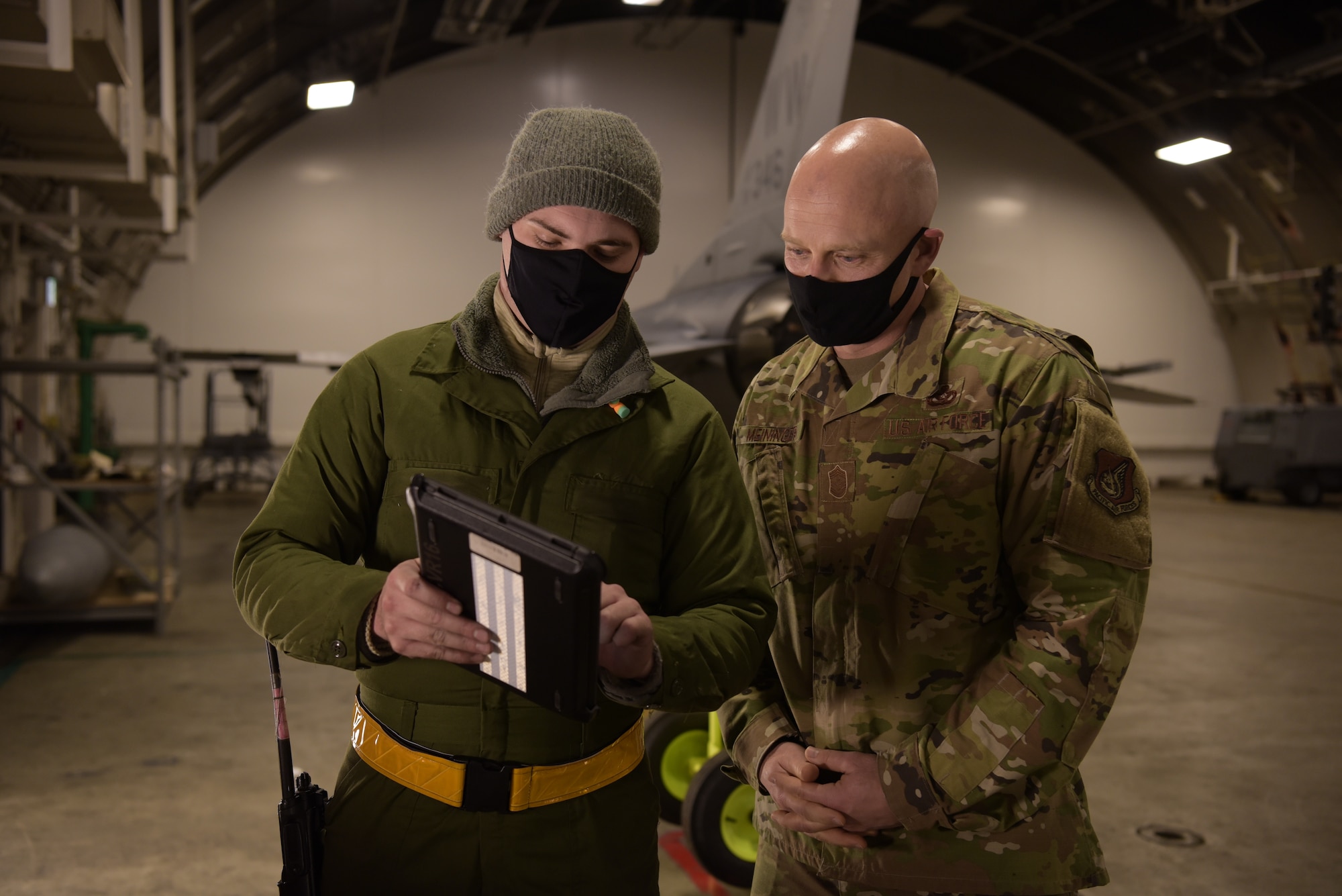 U.S. Air Force Tech. Sgt. Mark Ward, left, a 35th Aircraft Maintenance Squadron dedicated crew chief, shows Technical Orders on a tablet to Chief Master Sgt. Joey R. Meininger, right, 35th Fighter Wing command chief, during a Wild Weasel Walk-Through at Misawa Air Base, Japan, Dec. 29, 2020. “By the book” is taken seriously when it comes to maintaining aircraft. Technical Orders are simplified instructions Airmen follow precisely while performing maintenance on the F-16 Fighting Falcon. (U.S. Air Force photo by Airman 1st Class Joao Marcus Costa)