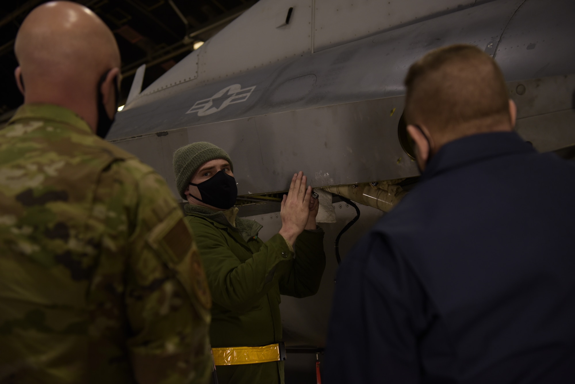 U.S. Air Force Tech. Sgt. Mark Ward, a 35th Aircraft Maintenance Squadron dedicated crew chief, explains the process of repairing a F-16 Fighting Falcon to Col. Jesse J. Friedel, right, the 35th Fighter Wing commander, and Chief Master Sergeant Joey R. Meininger, left, the 35th FW command chief, during a Wild Weasel Walk-Through at Misawa Air Base, Japan, Dec. 29, 2020. The wing being replaced is located on the back of the aircraft and it controls whether the plane goes up or down. (U.S. Air Force photo by Airman 1st Class Joao Marcus Costa)