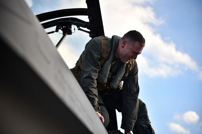 An Airman climbs out of a fighter aircraft.