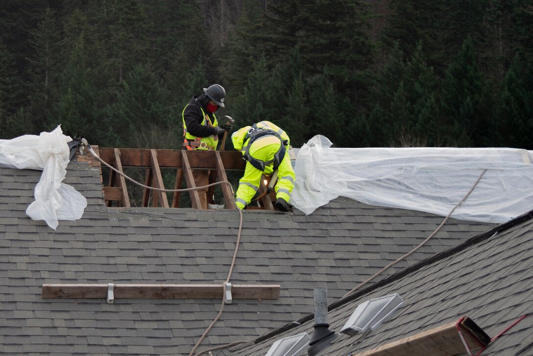 Workers remove the rain covering and prepare the Auditorium's roof before the crane lifts the cupola into place.