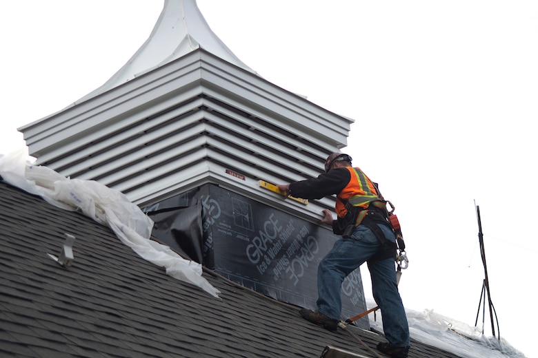 Workers inside and outside of the Auditorium building's new cupola guide it into place and ensure it is level.