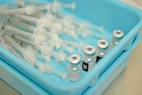 Syringes and small bottles of vaccine sit in a tray.