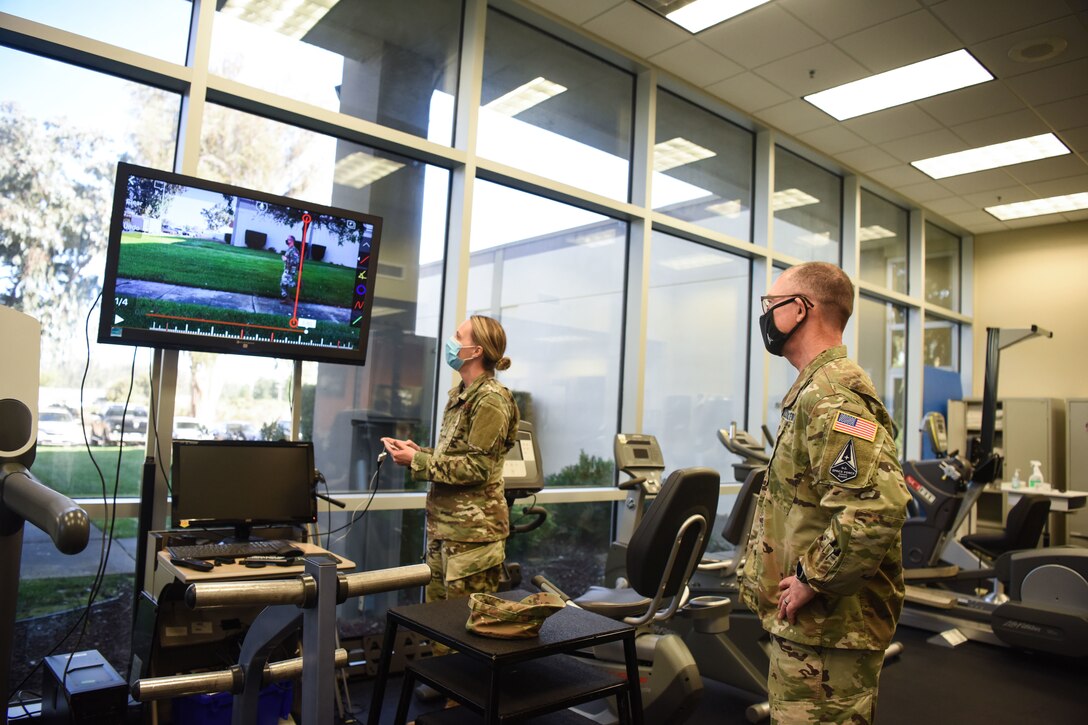 An airman briefs another airman while viewing a computer screen.