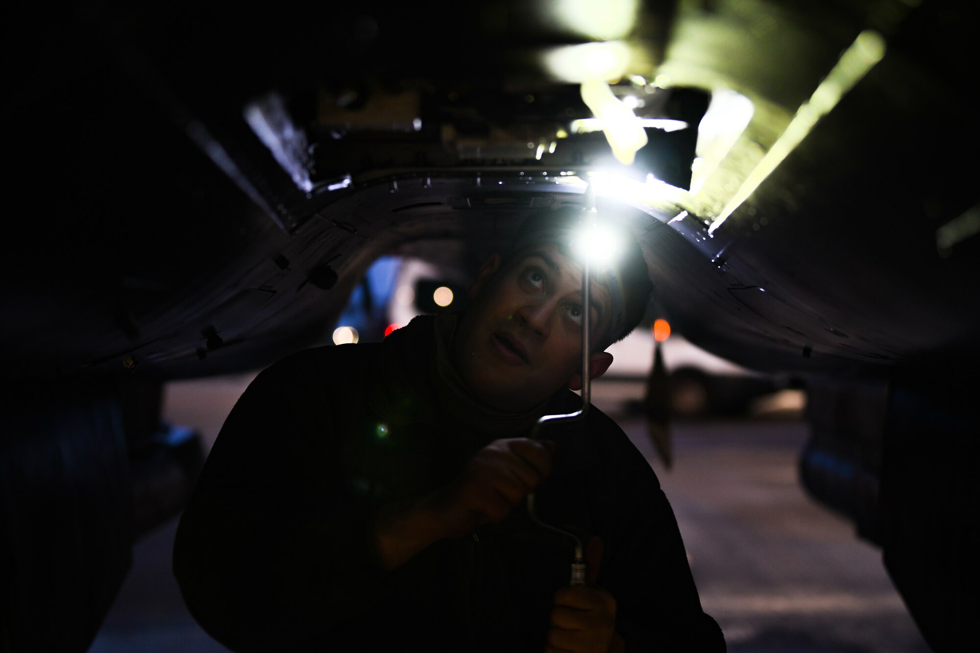 Staff Sgt. Brandon Thomas-Volkov, 494th Aircraft Maintenance Unit dedicated crew chief, tightens bolts to the underside of an F-15E Strike Eagle at Royal Air Force Lakenheath, England, Jan. 5, 2021. Dedicated Crew Chiefs are responsible for managing and supervising all maintenance on their respective aircraft by coordinating with other maintenance specialties such as propulsion, hydraulics and fuels to ensure the aircraft is operational in a timely manner. (U.S. Air Force photo by Senior Airman Madeline Herzog)