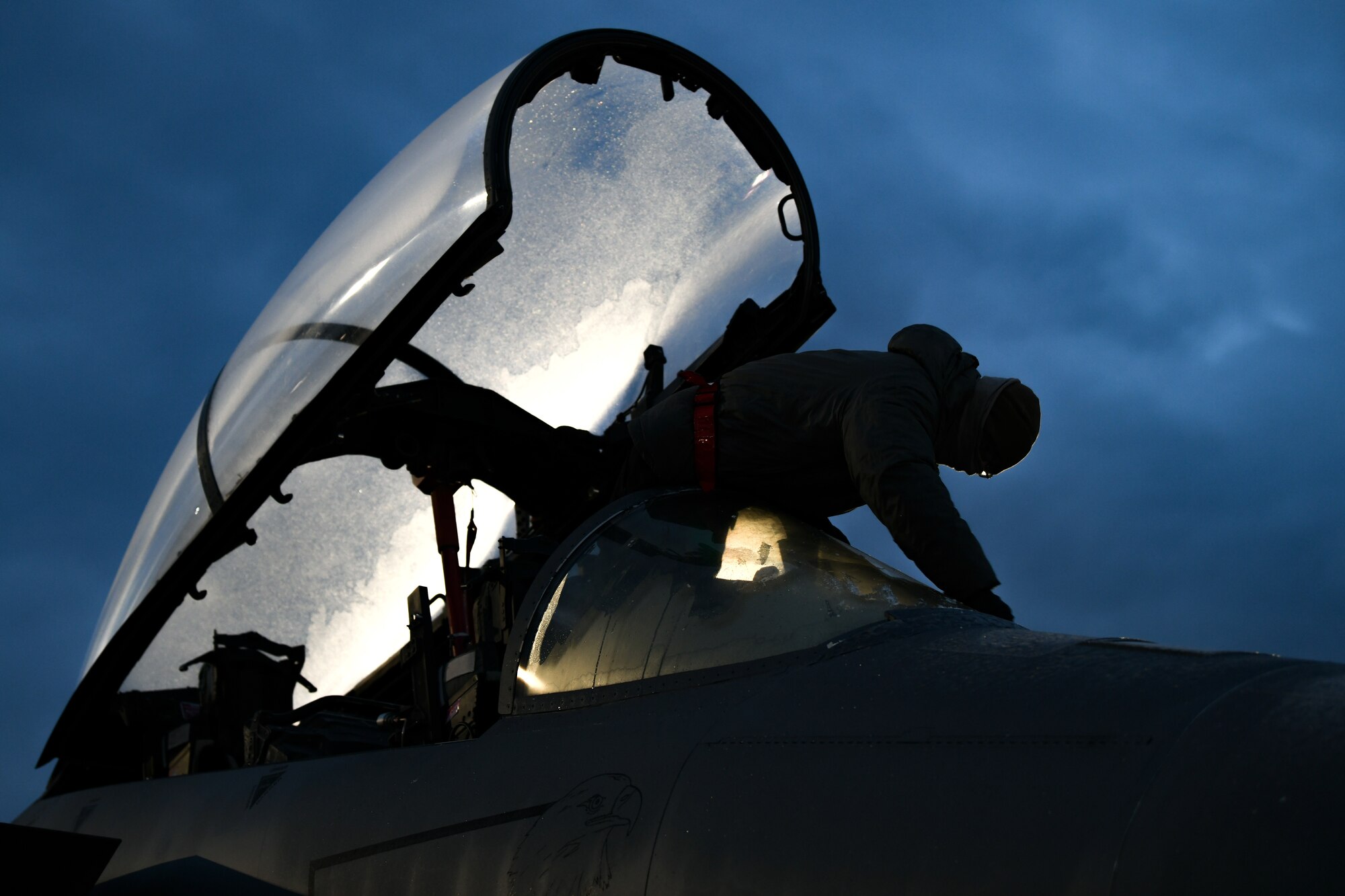 Airman 1st Class Matthew Perkins, 494th Aircraft Maintenance Unit assistant dedicated crew chief, scrapes the frost off of the canopy of an f-15E Strike Eagle before the first takeoffs of the new year at Royal Air Force Lakenheath, England, Jan. 5, 2021. ADCCs are responsible for supporting dedicated crew chiefs with all work pertaining to their aircraft. (U.S. Air Force photo by Senior Airman Madeline Herzog)