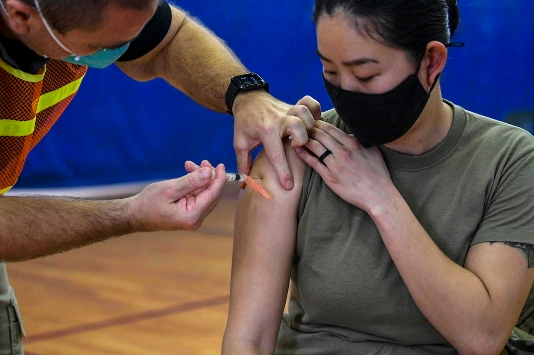 An airman gets with one sleeve rolled up gets a shot.