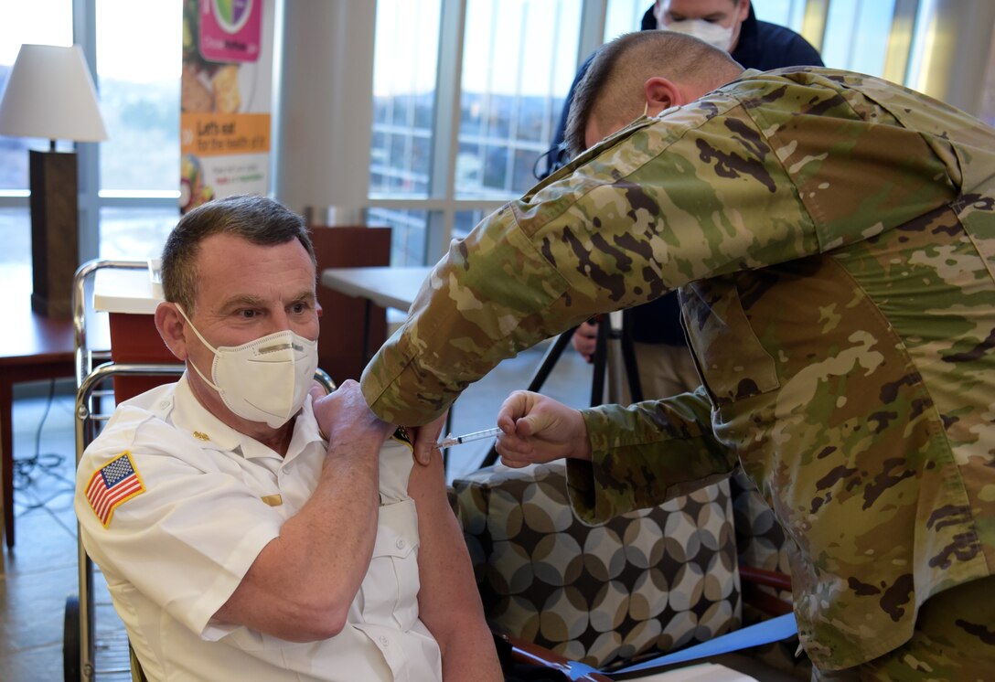 Man gets vaccination from a man in military uniform