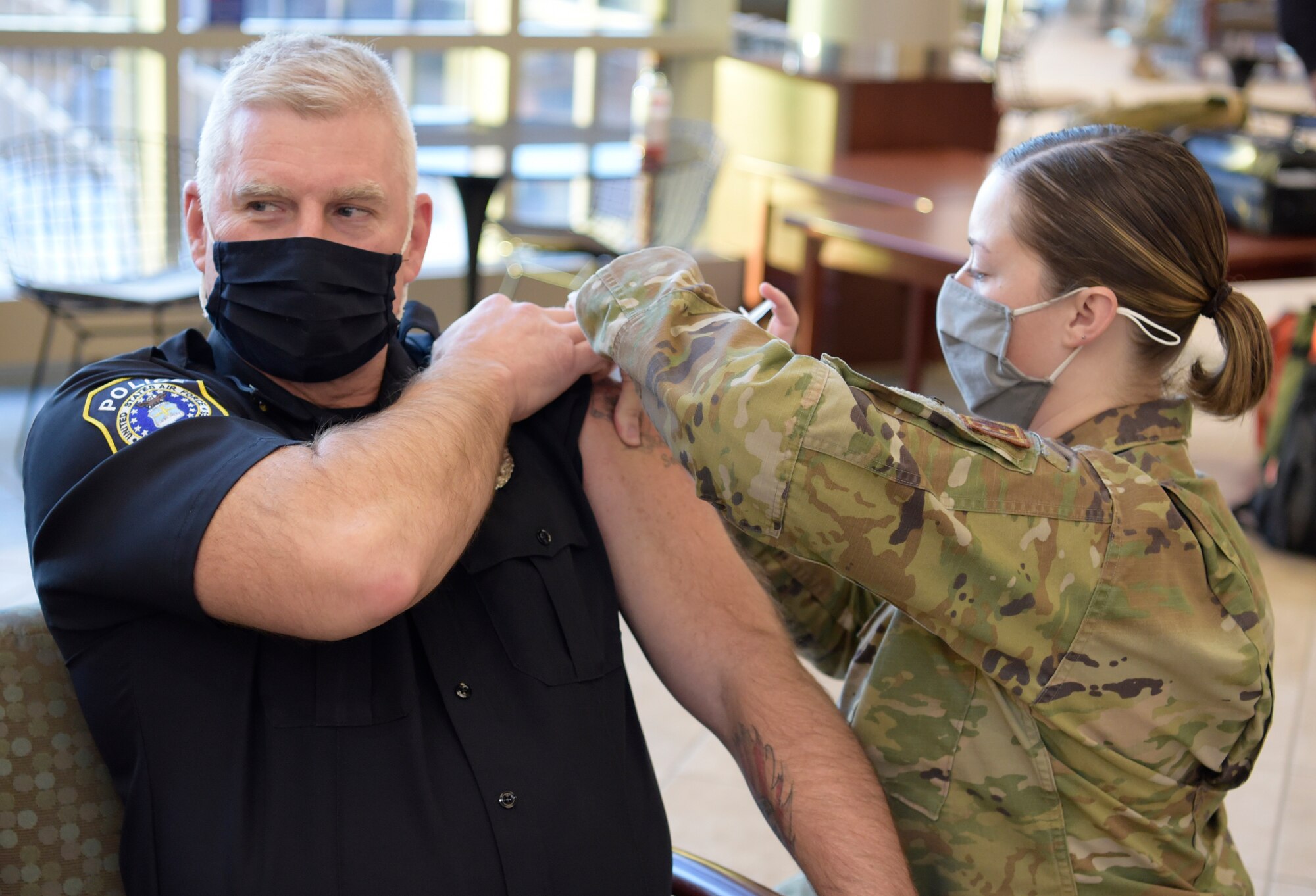Man gets vaccination from a woman in military uniform