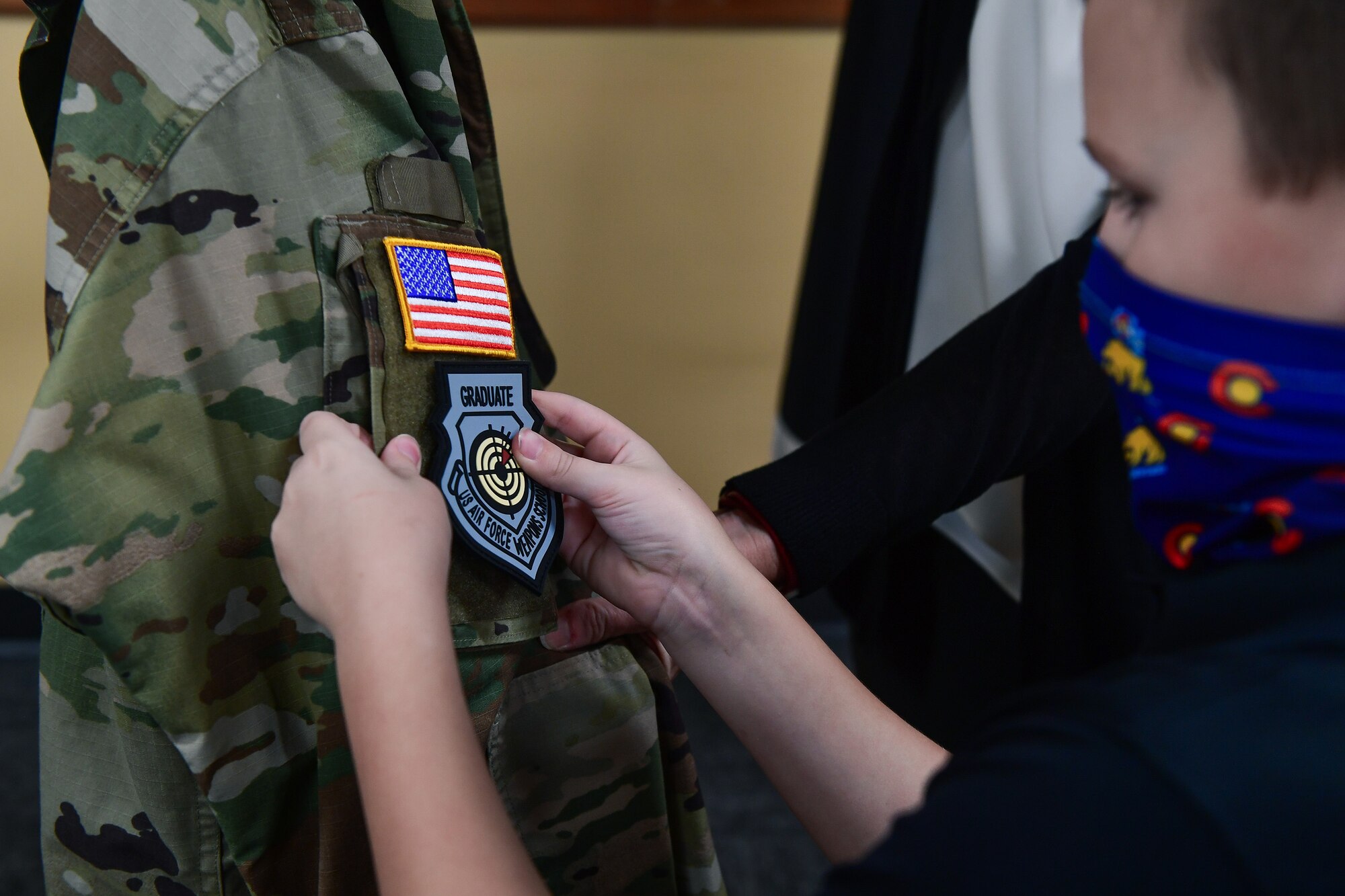 Col. Richard Bourquin, Space Delta 4 commander, has his U.S. Air Force Weapons School Graduate patch placed onto his Space Force uniform by his son, Bennett Bourquin, in the DEL 4 conference room at Buckley Air Force Base, Colo., Jan 5, 2021.