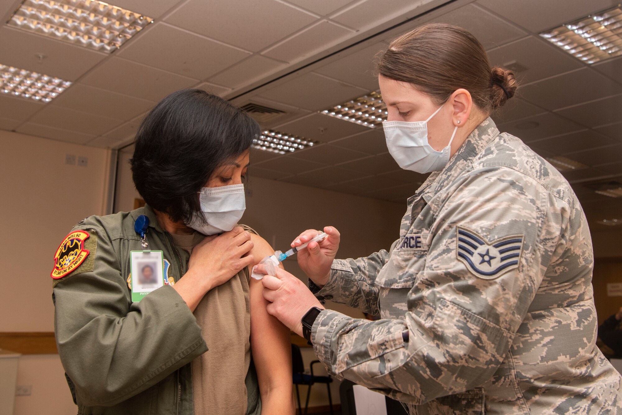 U.S. Air Force Staff Sgt. Anna Murray, 48th Healthcare Operations Squadron immunizations technician, administers a dose of the COVID-19 vaccine to Lt. Col. Rhodora Beckinger, 488th Intelligence Squadron flight surgeon, Jan. 5, 2021, at Royal Air Force Lakenheath, England. Beckinger was the first member of Team Mildenhall to receive the vaccine from the Air Force. (U.S. Air Force photo by Senior Airman Joseph Barron)