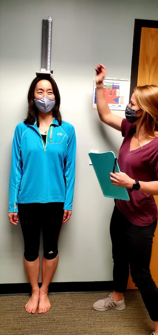 Fort Benning Army Wellness Center Health Educator McKenna Cornett weighs and measures the height of a patient.